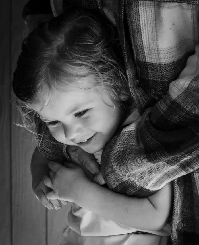 A smiling little girl wrapped in her parent's arms