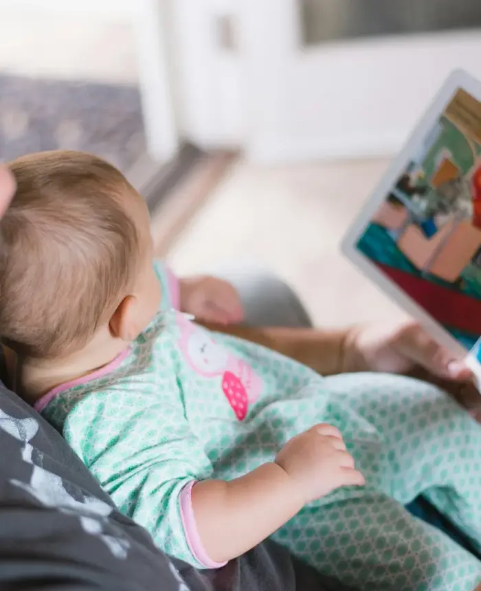A parent reading a picture book with a baby on their lap