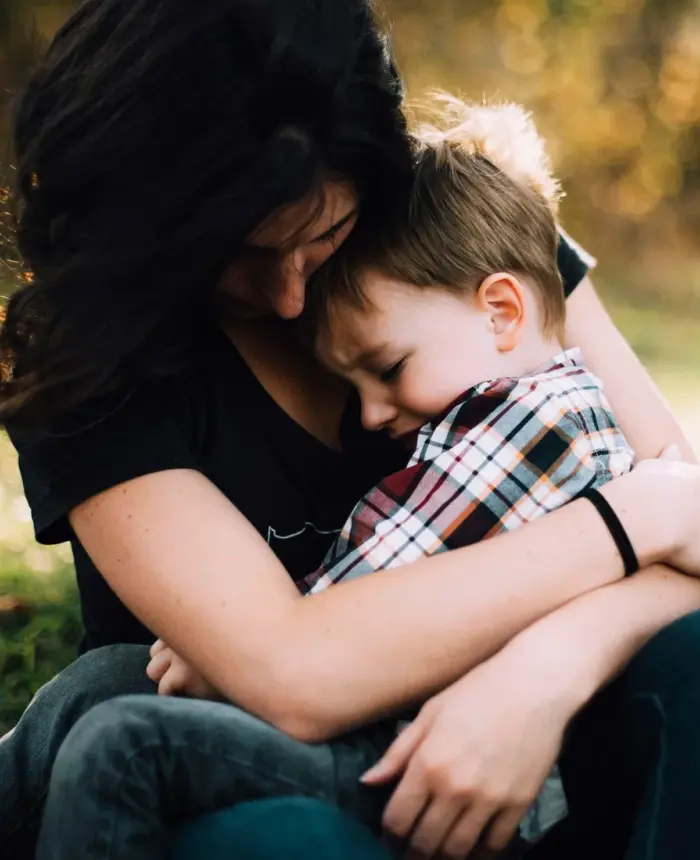 A mother hugging her young son on her lap