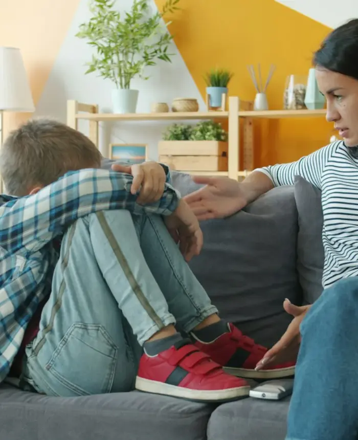 A parent comforting a distressed child on the sofa