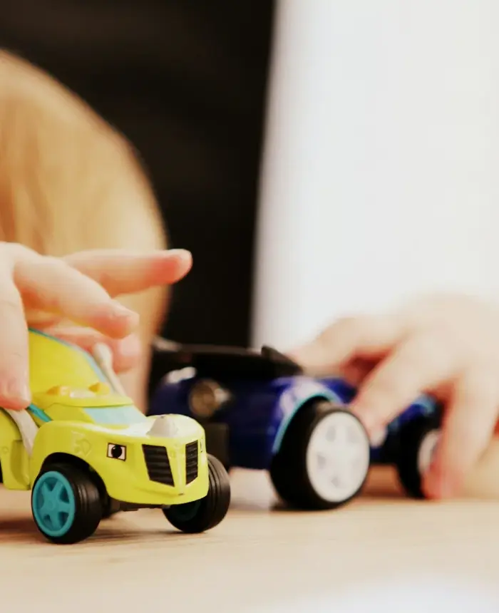 A young child playing with toy cars at a table